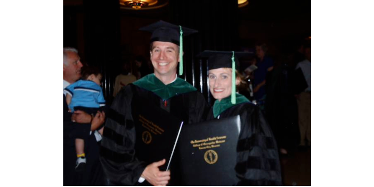 Shane Speights and Amanda Deel stand together in graduation attire with diplomas.